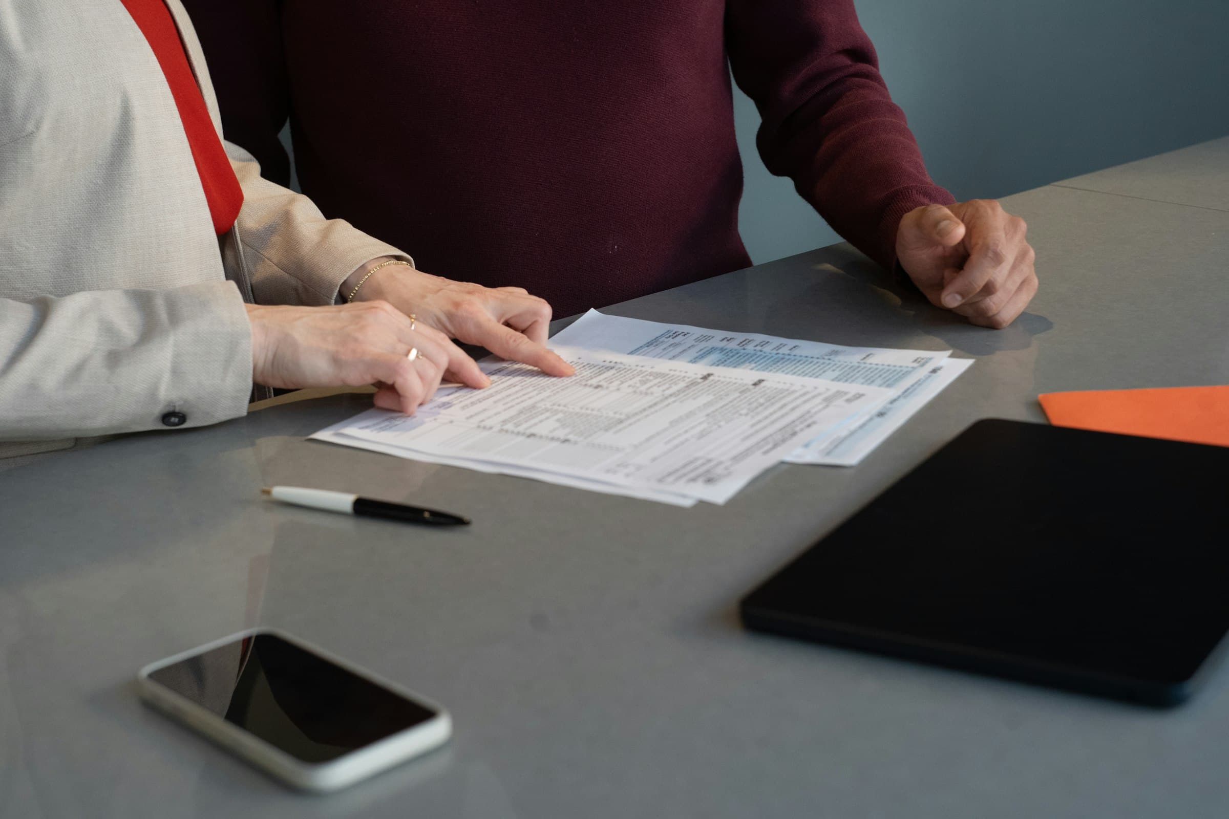 Two people reviewing printed documents across a meeting table